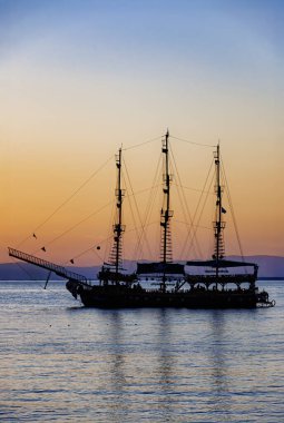 Günbatımı gökyüzü tarafından siluetlenmiş bir korsan gemisi..