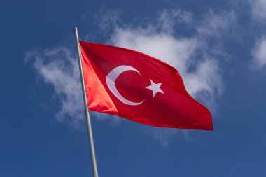 Türk bayrağı beyaz bulutlu mavi gökyüzüne karşı bayrak direğinde
