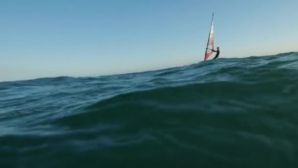 Sport nautique. Windsurfer tourne près du chemin solaire à partir du coucher du soleil à l'arrière-plan du ciel orange — Video