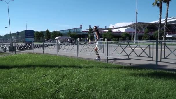 Jeune hipster habillé bruenette sauter par-dessus une clôture dans le parc à zone non-allouée et plier les règles — Video