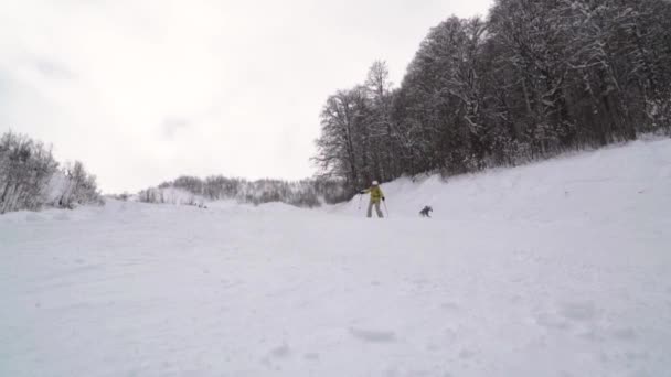 Медленное движение сноубордиста, одетого в яркую одежду, вызывает снежные волны и бросает снег на камеру. Сноубордист в оранжевой одежде едет на пустой лыжной трассе . — стоковое видео