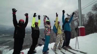 Grup kayakçı kask ve parlak ekipman giymiş bir kameraya bakarak bir ans tarafından bekliyoruz. Snowboard tehlikeye eller yukarı hep birlikte. Kayakçı çok komik tamamen dans ediyor.