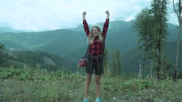 Bella ragazza vittoriosamente mettere le mani in alto e ridere mentre viene nella zona aperta in montagna. Escursioni estive in montagna. Vacanze estive e avventura . — Video Stock