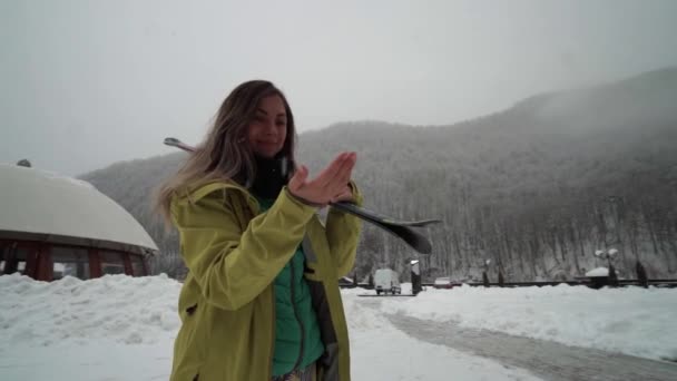 Meisje bereidt om te skiën. Jonge vrouwelijke skiër geniet sneeuwvlokken gedaald uit de hemel. Sneeuwvlokken vallen aan de hand. — Stockvideo