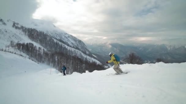 La esquiadora cabalga a través del borde de las montañas frente a picos fascinantes . — Vídeos de Stock
