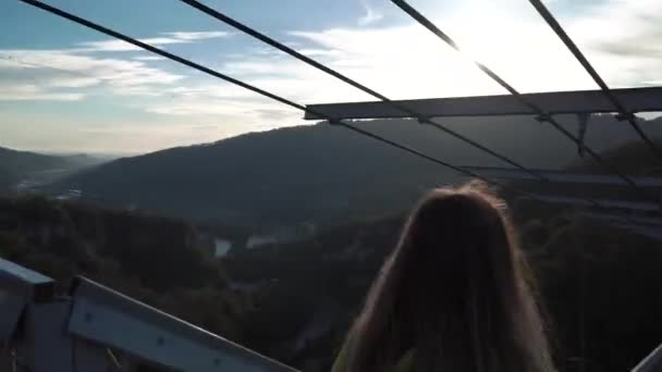 Cutie νεαρή κοπέλα κλήση να πάει για έναν περίπατο μαζί της μέσω αερογέφυρας huse. Νεαρή κοπέλα απολαμβάνοντας περπατώντας skypark — Αρχείο Βίντεο