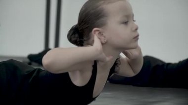 Siyah mayo yakın çekim sevimli küçük dansçı çapraz kolları ve klasik dans öğretmeni bekleyen ile katta yatıyor