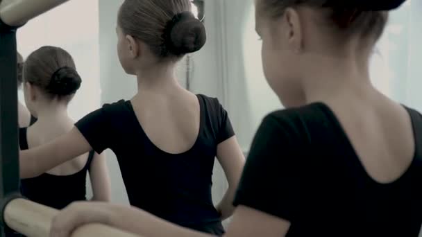 Primer plano de las manos de las pequeñas bailarinas vestidas con trajes negros. Primer plano de las manos sosteniendo una barra de ballet — Vídeos de Stock