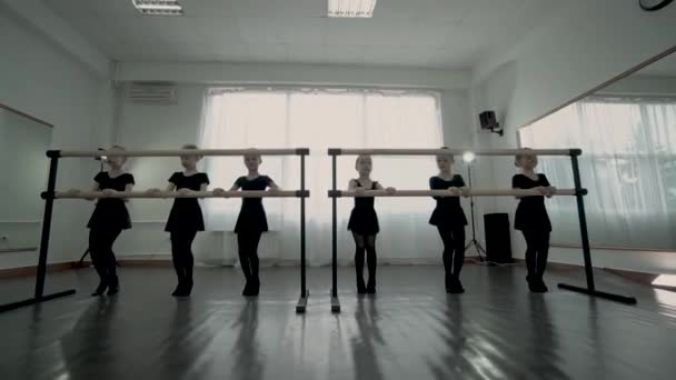 Kleine traurige Ballerinen in schwarzen Trikots, die ganz langweilige Übungen in der Nähe von Ballettbarren machen — Stockvideo