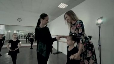 Genç anne çocuk dans sınıfı öğretmeni selamlıyorum. Anne kızını dans kursuna götürür. İlk adım bale dersi. Öğretmen Selamlıyorum yeni küçük balerin ve annesi dans sınıfı.
