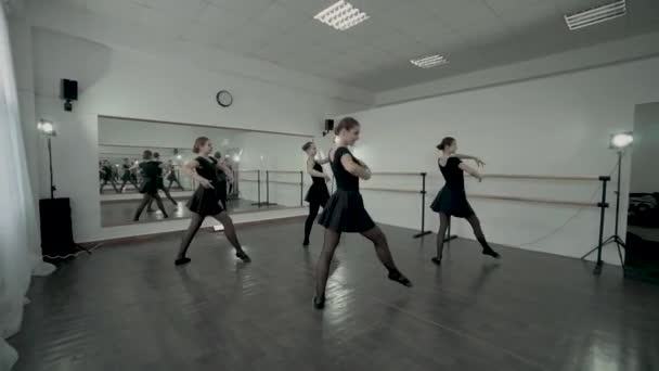 Adolescentes bailarinas vestidas com leotards pretos fazem movimento de balé completamente enquanto o professor olha para eles . — Vídeo de Stock