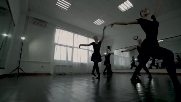 Bailarinas de tiro de bajo ángulo vestidas con los leotardos negros giran. Bailarinas hacen un PIROUTTE . — Vídeo de stock