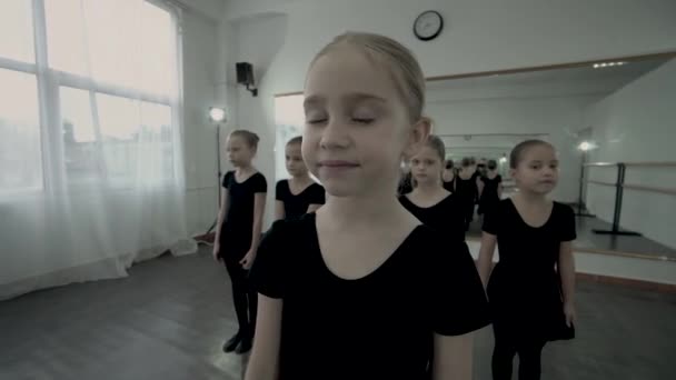 Blonde little ballerina stand at front of other ballerinas and have a dream with the closed eyes. Dancer dreaming about success. Dancers dreams come true. — Stock Video