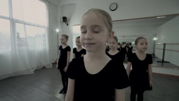 A pequena bailarina loira está na frente de outras bailarinas e tem um sonho com os olhos fechados. Dançarina sonhando com sucesso. Dançarinos sonhos se tornam realidade . — Vídeo de Stock