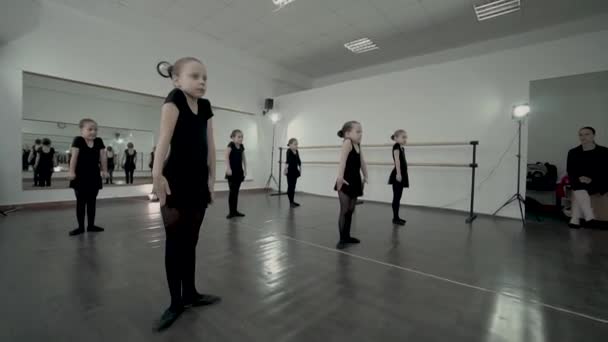 Los niños están escuchando a esos técnicos de baile y haciendo el mismo movimiento por completo. Los niños se están calentando en la clase de baile. Los niños mueven esos portaobjetos hacia arriba y hacia abajo al mismo tiempo. Bailarinas vestidas — Vídeo de stock