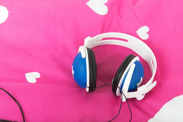 Head phones laying om pink bed