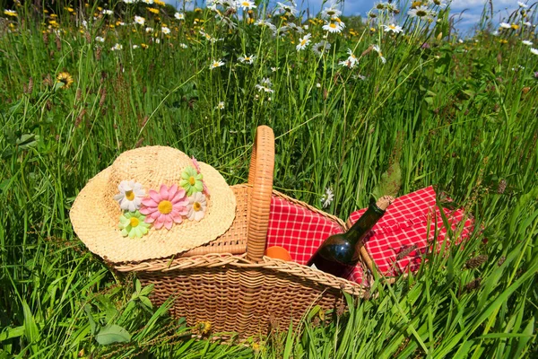 夏日花丛中的野餐篮稻草帽和雏菊 — 图库照片
