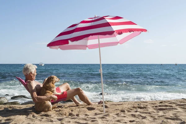 Älterer Mann Sonnt Sich Mit Hund Strand Unter Sonnenschirm Mit — Stockfoto