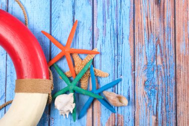 Ahşap arka planda deniz yıldızları ve can simidi olan plaj posteri.