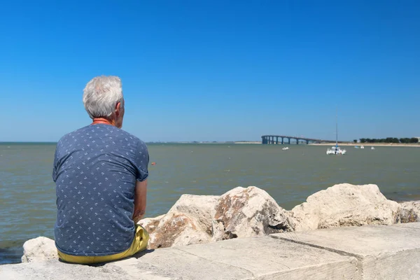 Homem Sênior Sentado Costa Olhando Para Ponte Para Ilha Continental — Fotografia de Stock