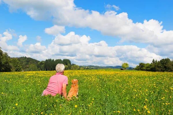 Man with dog sitting in landscape — Stock Photo, Image
