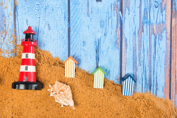 Lighthouse and beach huts in sand — Stock Photo, Image