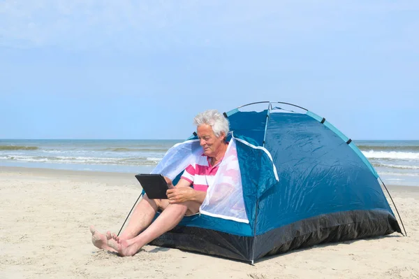 Άνθρωπος με ψηφιακό tablet camping σε καταφύγιο στην παραλία — Φωτογραφία Αρχείου