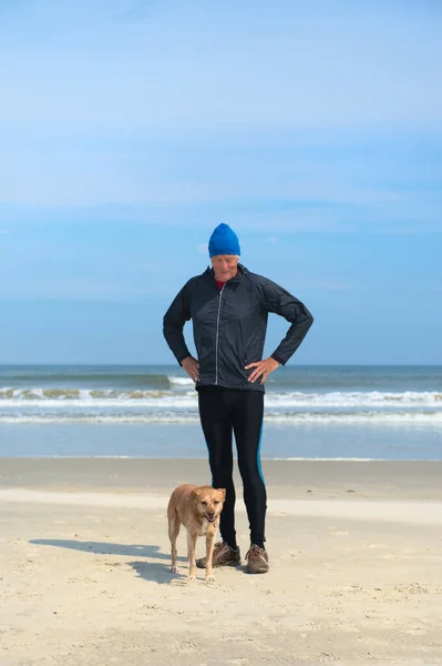 Senior man sporting with dog at beach — Stock Photo, Image