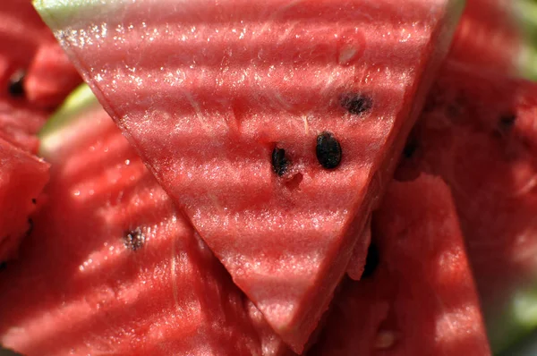 Haufen saftiger Wassermelonenscheiben in gestreiftem Licht — Stockfoto