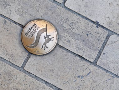 Orleans, Fransa'nın sokaklarında ve kaldırımlarında küçük yuvarlak bakır plaka, farklı dillerde şehrin adı ve atının üzerinde Joan of Arc soyut görüntü ile
