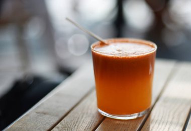 Sağlıklı portakal meyvesi ve ahşap masada saman bulunan sebze suyu. Seçici odak