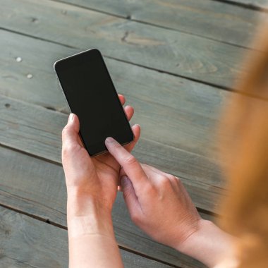 Ahşap arka plan üzerinde telefon holding eller. Yukarı alay.