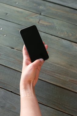 Ahşap arka plan üzerinde telefon holding eller. Yukarı alay.