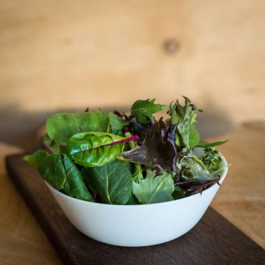 Ahşap arka plan üzerinde bir tabak içinde taze yaprakları karışımı gelen vejetaryen salata