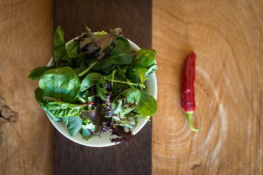 Ahşap arka plan üzerinde bir tabak içinde taze yaprakları karışımı gelen vejetaryen salata