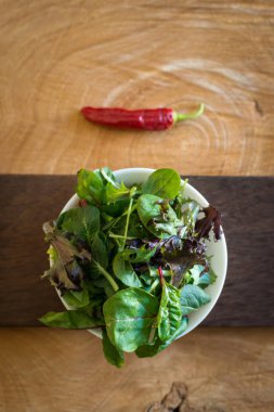 Ahşap arka plan üzerinde bir tabak içinde taze yaprakları karışımı gelen vejetaryen salata