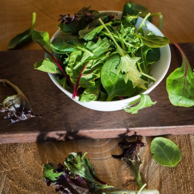 Ahşap arka plan üzerinde bir tabak içinde taze yaprakları karışımı gelen vejetaryen salata