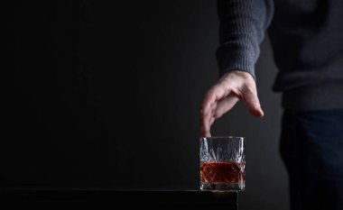 Adamın elinde bir bardak alkol için ulaşır. Alkolizm konusunda kavramsal görüntü. Metniniz için kopya alanı.