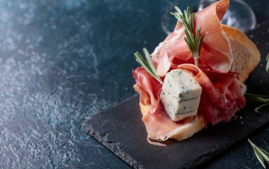 Jambon, mavi peynir ve karanlık bir arka plan üzerinde biberiye ile sandviç. Metniniz için kopya alanı.