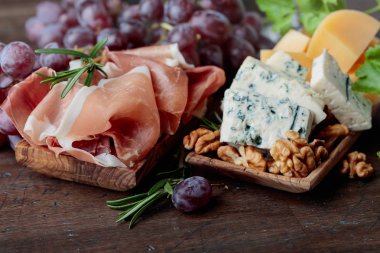 Çeşitli peynirler, üzüm ve prosciutto eski bir ahşap tablo.