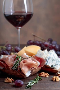 Prosciutto biberiye ve eski ahşap bir masa üzerinde kırmızı şarap ile.