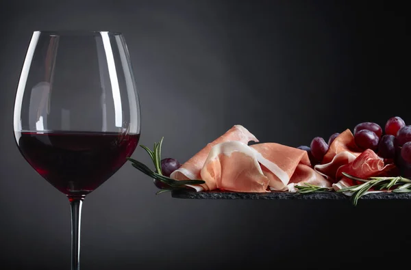 産生ハムとローズマリーと古い木製のテーブルの赤ワインのガラス — ストック写真