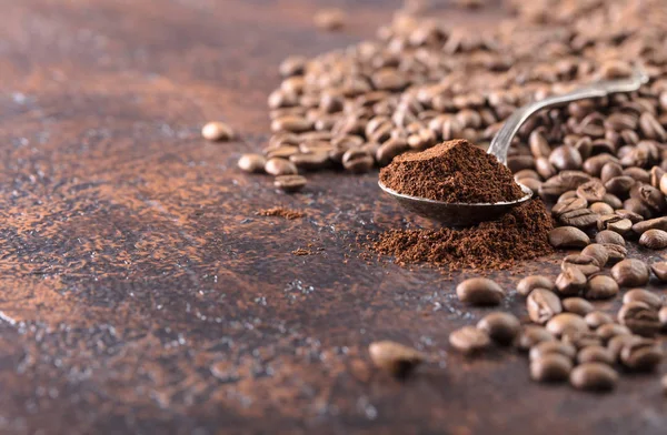 Black roasted coffee grains and ground coffee in spoon lie on a copper table, copy space for your text.