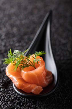 Siyah susam arka plan üzerine dereotu ile tuzlanmış somon dilim.