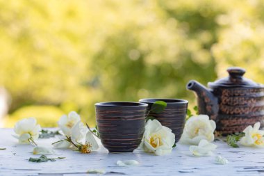 Seramik bardak, Çaydanlık ve beyaz köpek gül bahçesinde eski ahşap bir masa üzerinde. Yabani gül ile aromatik ve canlandırıcı çay.