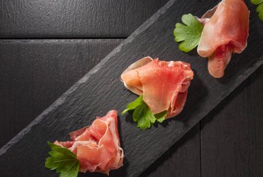 Prosciutto maydanoz siyah bir tablo ile. Üstten görünüm, kopya alanı. 