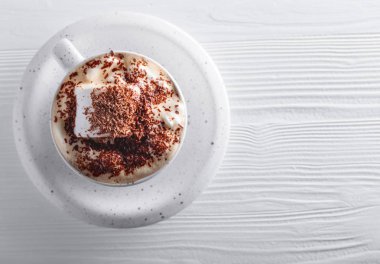 Beyaz ahşap masaya çikolata parçacıkları serpiştirilmiş sıcak çikolata ve lokum. Boşluğu kopyala, üst görünüm .