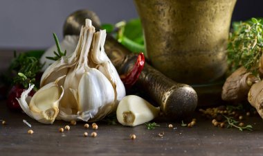 Sarımsak ve ahşap bir masa üzerinde farklı baharatlar. Eski bakır havan topu baharat .