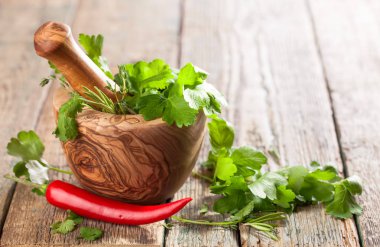  Ahşap harç biberiye, kişniş, kekik ve maydanoz ile. Eski ahşap bir masa üzerinde Warious otlar .