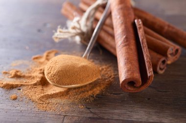 Kaşık toz tarçın ve eski ahşap bir masa üzerine tarçın ile.